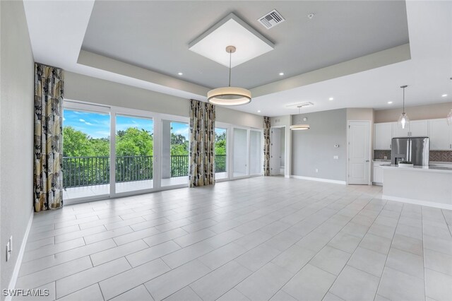 unfurnished living room featuring a tray ceiling and light tile patterned flooring