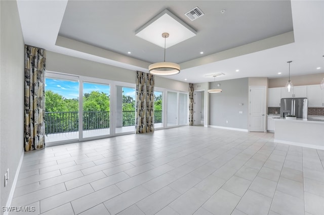 unfurnished living room featuring light tile patterned floors, recessed lighting, visible vents, baseboards, and a raised ceiling