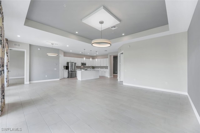 unfurnished living room with a raised ceiling and visible vents