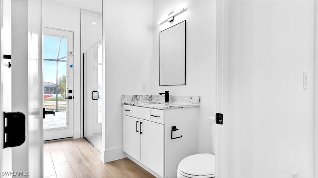 bathroom featuring a stall shower, vanity, toilet, and wood finished floors