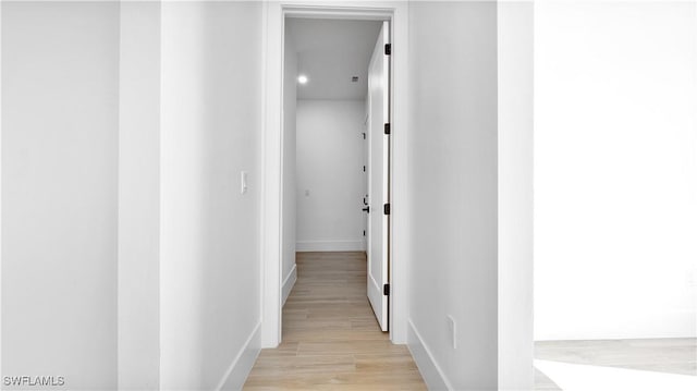 corridor with light wood-type flooring and baseboards