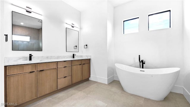 bathroom featuring double vanity, a freestanding tub, baseboards, and a sink