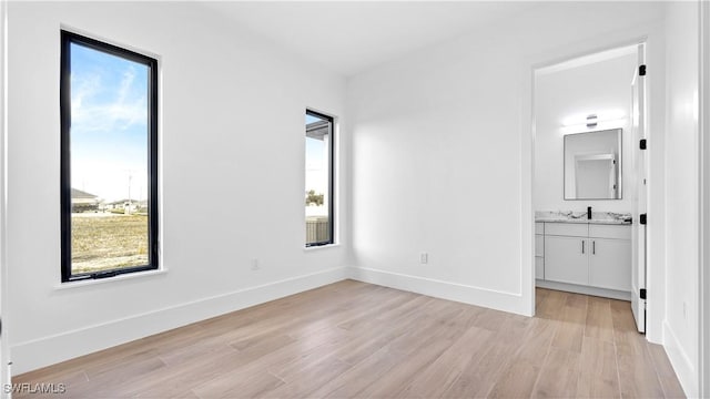 unfurnished bedroom with multiple windows, light wood-type flooring, and baseboards