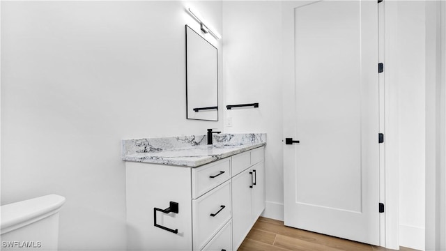 bathroom featuring vanity, toilet, and wood finished floors