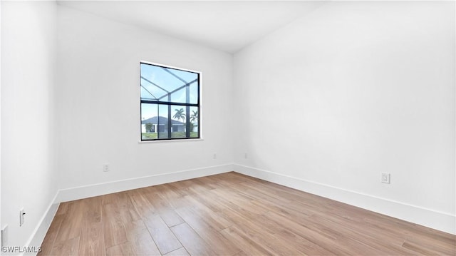 spare room featuring baseboards and light wood-style floors