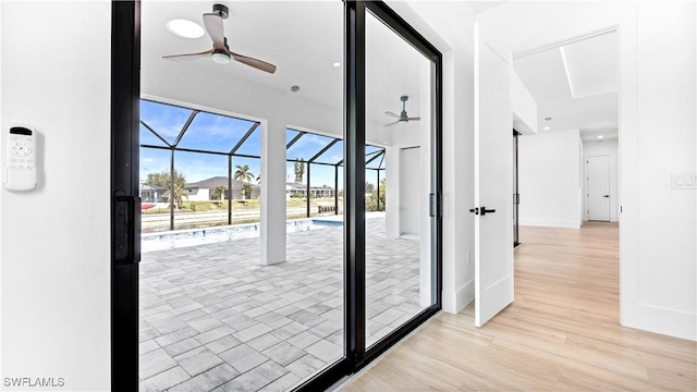 entryway featuring light wood-style flooring, baseboards, ceiling fan, and a sunroom