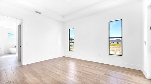 empty room with a healthy amount of sunlight, visible vents, and light wood-style flooring