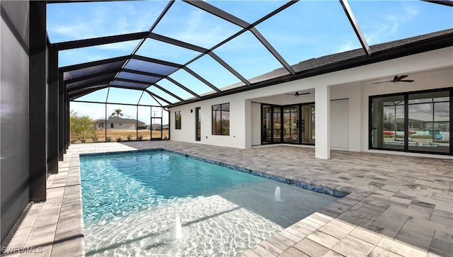 outdoor pool with glass enclosure, a ceiling fan, and a patio