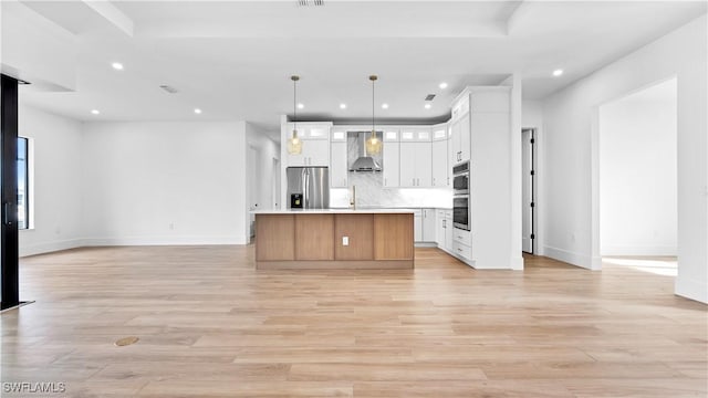 kitchen with recessed lighting, stainless steel appliances, open floor plan, and wall chimney range hood