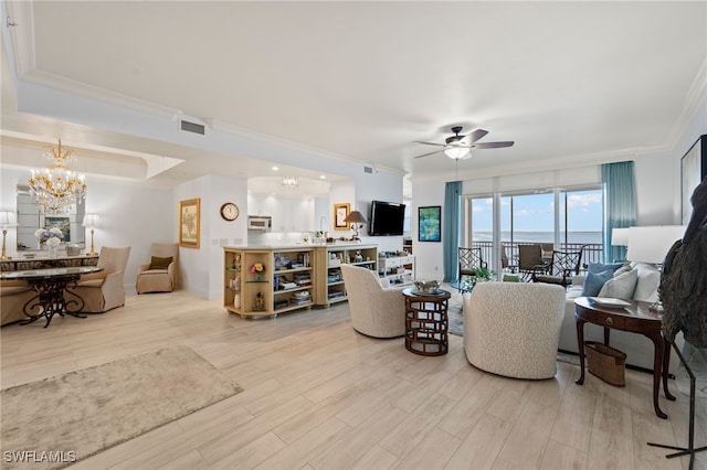 living room featuring ceiling fan with notable chandelier, light hardwood / wood-style floors, a raised ceiling, and crown molding