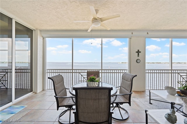 sunroom / solarium featuring ceiling fan and a water view