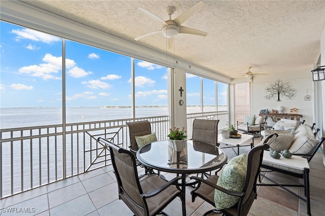 sunroom featuring ceiling fan and a water view