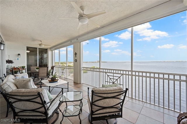 sunroom featuring ceiling fan and a water view