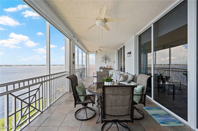 sunroom / solarium with ceiling fan and a water view