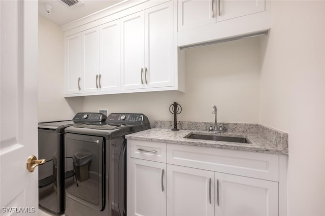 laundry room featuring washer and dryer, cabinet space, and a sink