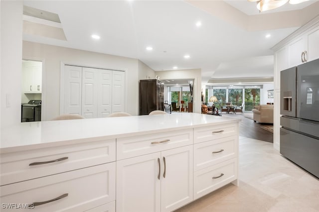 kitchen with light countertops, washer and dryer, white cabinets, and fridge with ice dispenser