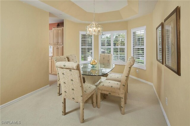 carpeted dining space featuring a raised ceiling and a chandelier