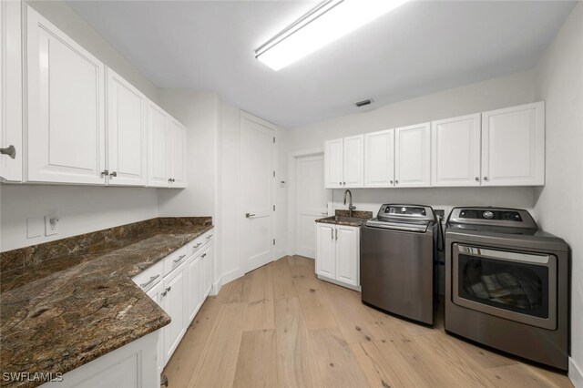 laundry area featuring sink, independent washer and dryer, cabinets, and light hardwood / wood-style floors