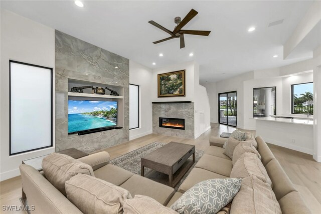 living room with light hardwood / wood-style floors, a fireplace, and ceiling fan