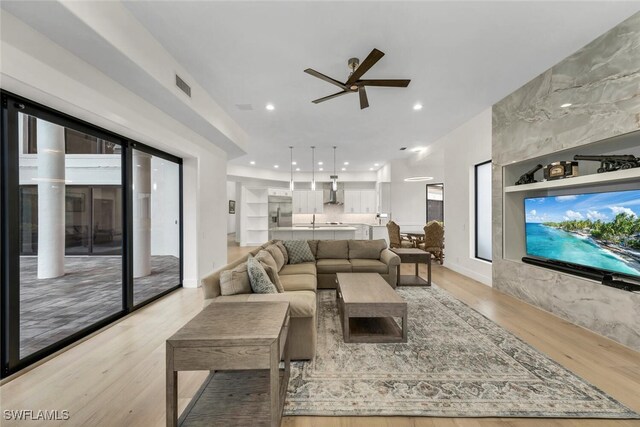 living room featuring built in shelves, light hardwood / wood-style floors, and ceiling fan