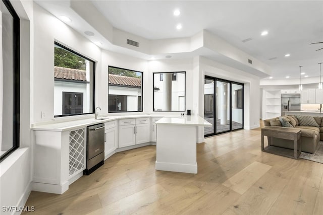 kitchen featuring appliances with stainless steel finishes, light hardwood / wood-style flooring, hanging light fixtures, white cabinets, and a center island