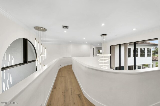 corridor featuring ornamental molding and light hardwood / wood-style floors