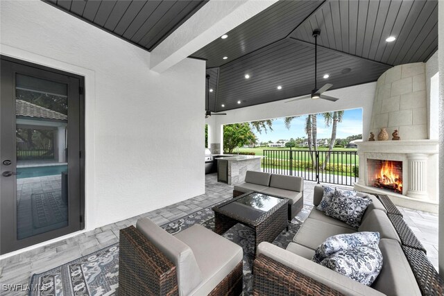 view of patio with an outdoor living space with a fireplace and ceiling fan