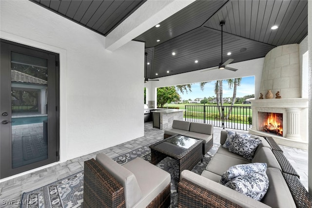 view of patio featuring ceiling fan, exterior kitchen, and an outdoor living space with a fireplace