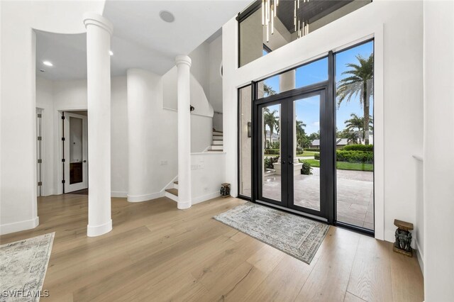 foyer entrance with light hardwood / wood-style floors and decorative columns