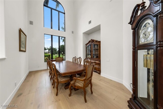 dining area with a high ceiling and light hardwood / wood-style flooring