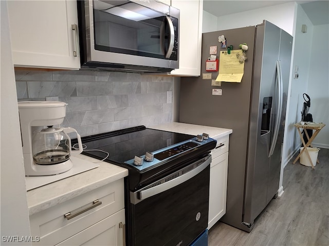 kitchen featuring white cabinets, appliances with stainless steel finishes, light wood-type flooring, and tasteful backsplash