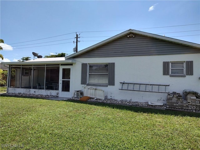 rear view of property featuring a sunroom and a lawn