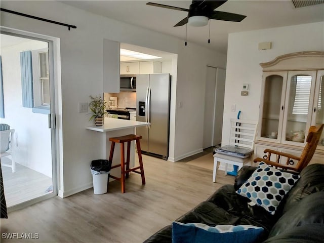 living room featuring ceiling fan and light wood-type flooring