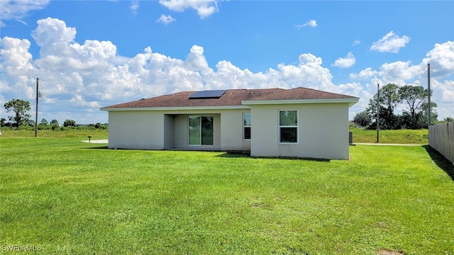 back of house featuring a lawn and solar panels