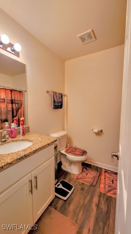 bathroom with wood-type flooring, vanity, and toilet