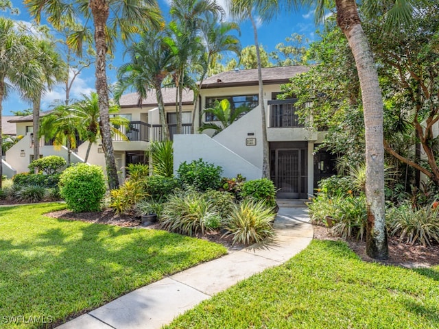 view of front of house featuring a front yard and a balcony