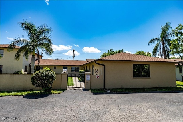 ranch-style home with a fenced front yard, a gate, and stucco siding