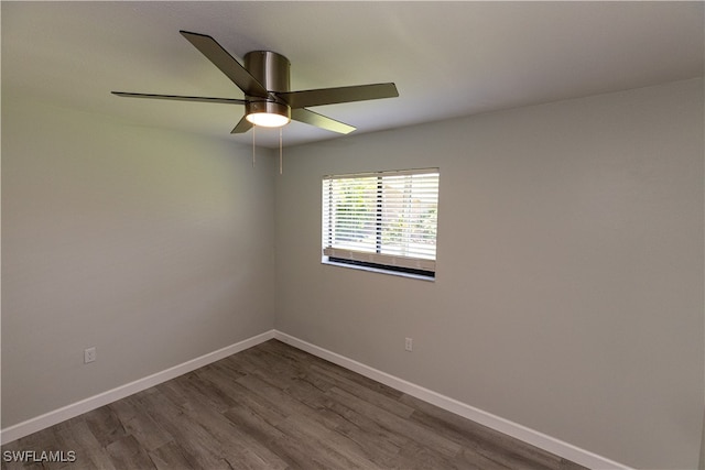 empty room featuring a ceiling fan, baseboards, and dark wood-type flooring