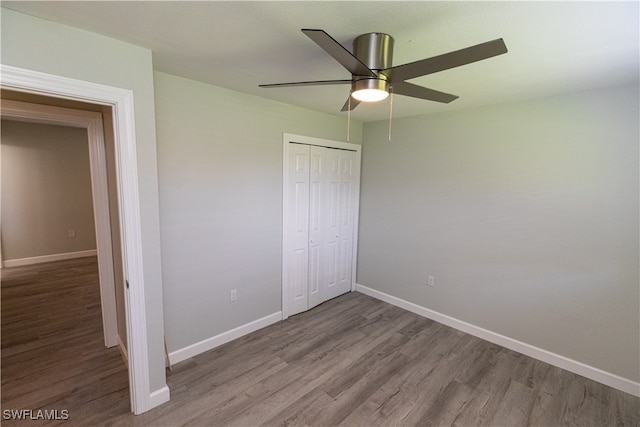 unfurnished bedroom featuring a closet, wood finished floors, a ceiling fan, and baseboards