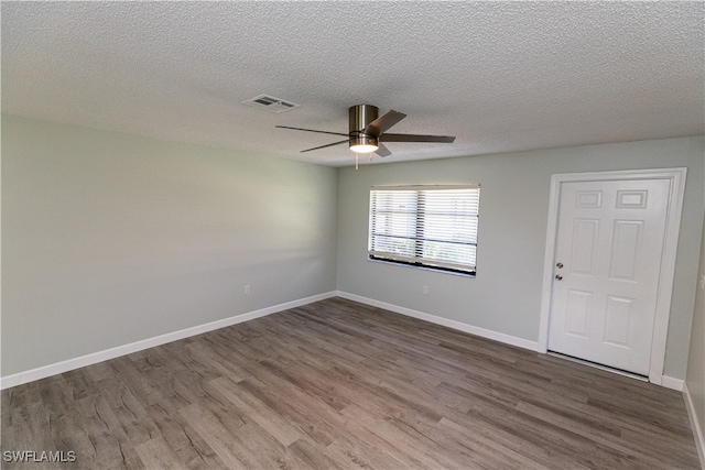 empty room featuring visible vents, dark wood finished floors, baseboards, and ceiling fan