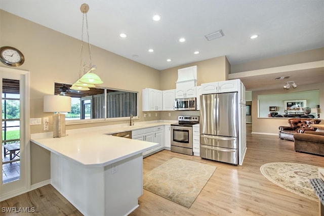 kitchen with hanging light fixtures, white cabinetry, kitchen peninsula, stainless steel appliances, and light wood-type flooring