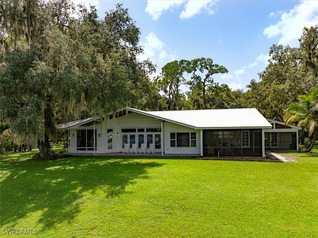 rear view of house featuring a yard and a sunroom