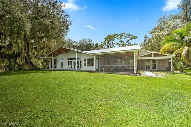 rear view of property with a lawn and a sunroom