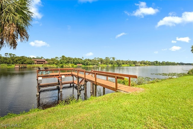 view of dock with a lawn and a water view