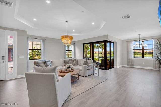 living room featuring a raised ceiling, hardwood / wood-style flooring, and a notable chandelier