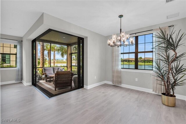 unfurnished dining area featuring hardwood / wood-style floors, a water view, and a chandelier