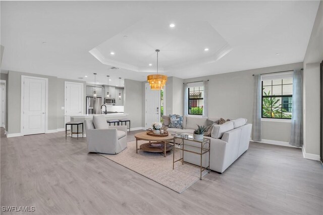 living room featuring a healthy amount of sunlight, light hardwood / wood-style flooring, and a tray ceiling