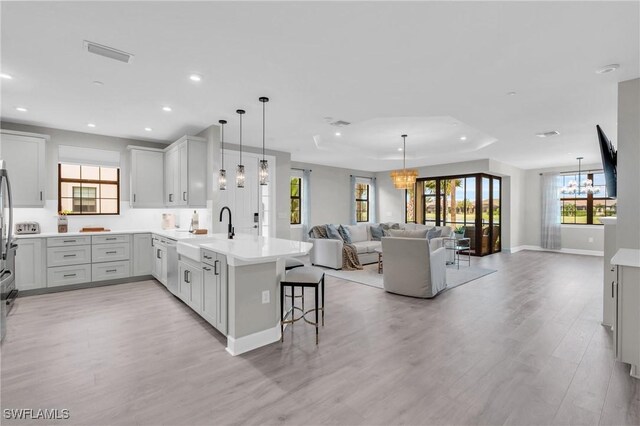 kitchen featuring kitchen peninsula, a breakfast bar, sink, light hardwood / wood-style flooring, and a chandelier