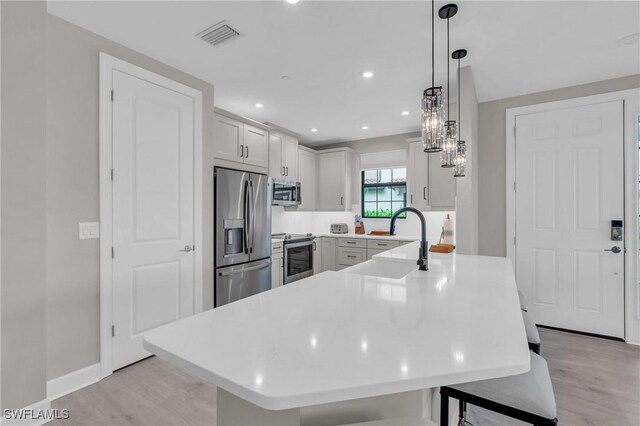 kitchen featuring pendant lighting, light hardwood / wood-style floors, sink, and appliances with stainless steel finishes