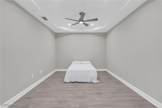 unfurnished bedroom featuring a tray ceiling, ceiling fan, and light hardwood / wood-style flooring